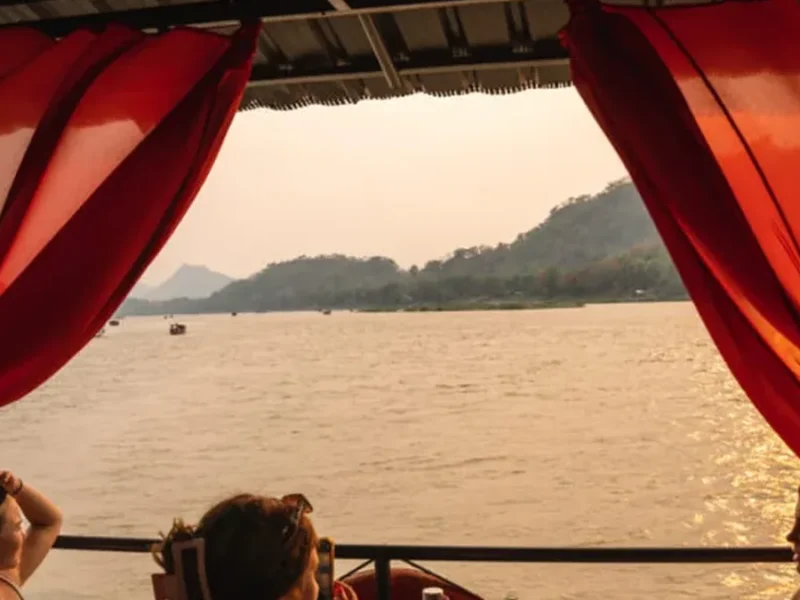 Travelers relaxing on a scenic river boat in Laos during a flexible private journey.