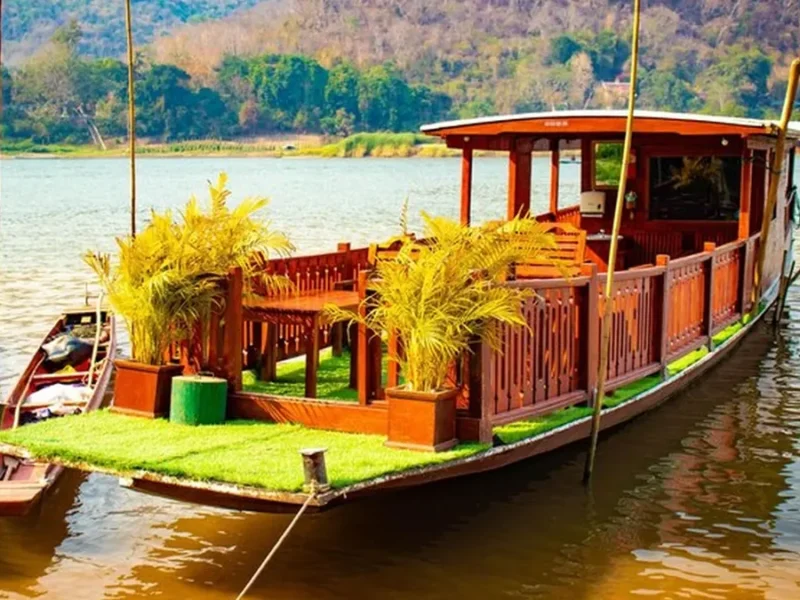 Traditional wooden boat on a quiet Laos river, illustrating a slow Mekong journey.